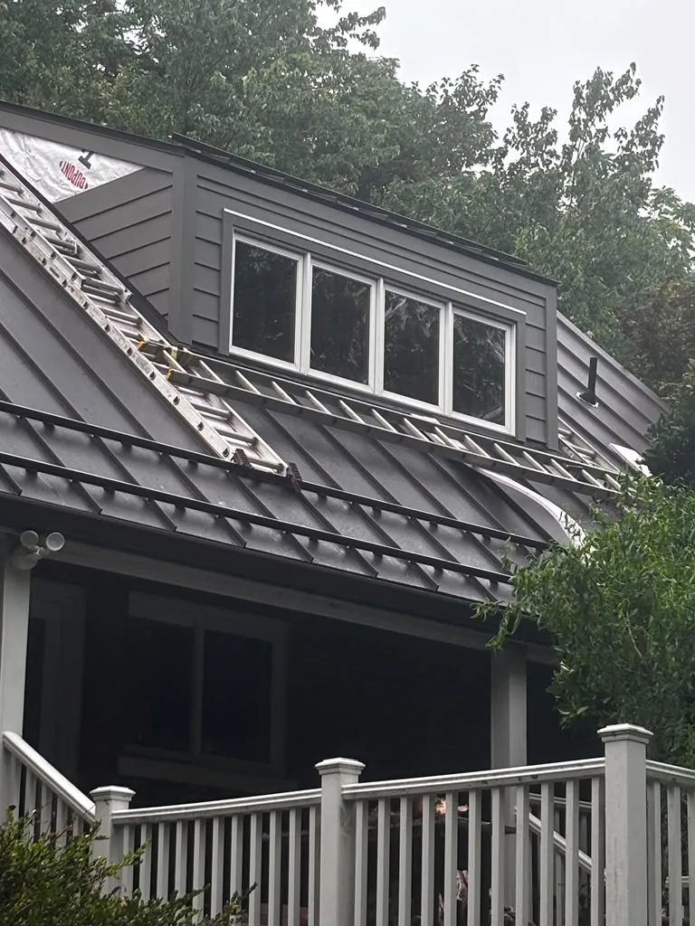 Dark standing-seam metal roof and board and batten dormer siding