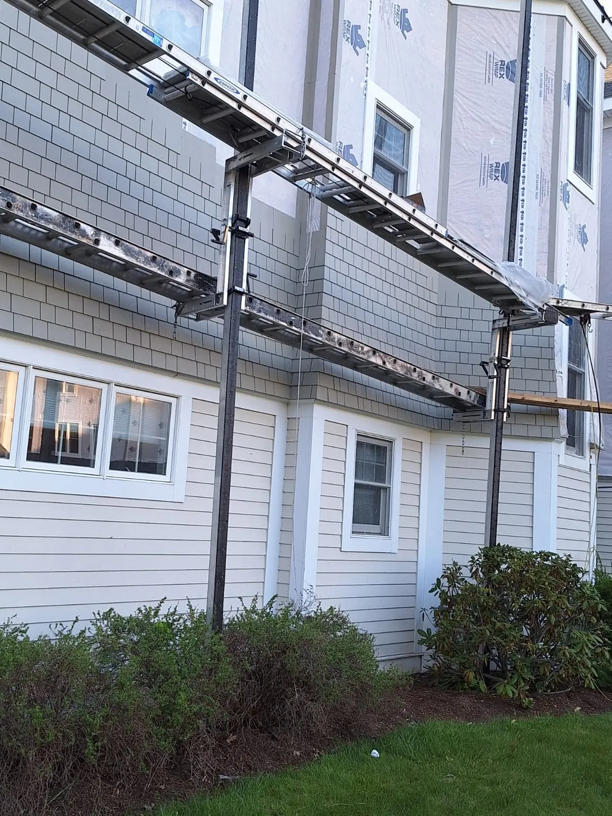 Scaffold setup for cedar shake siding installation on a two-story home