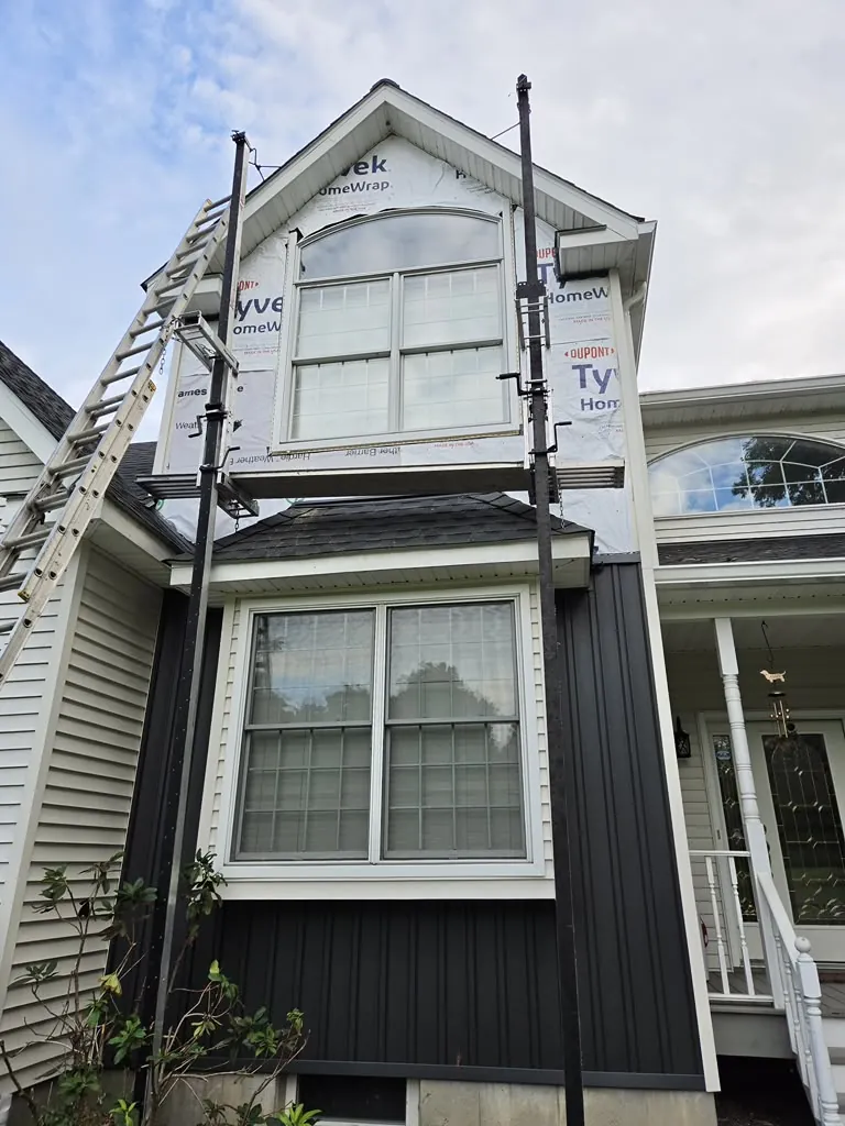 Dormer siding installation in progress with house wrap visible