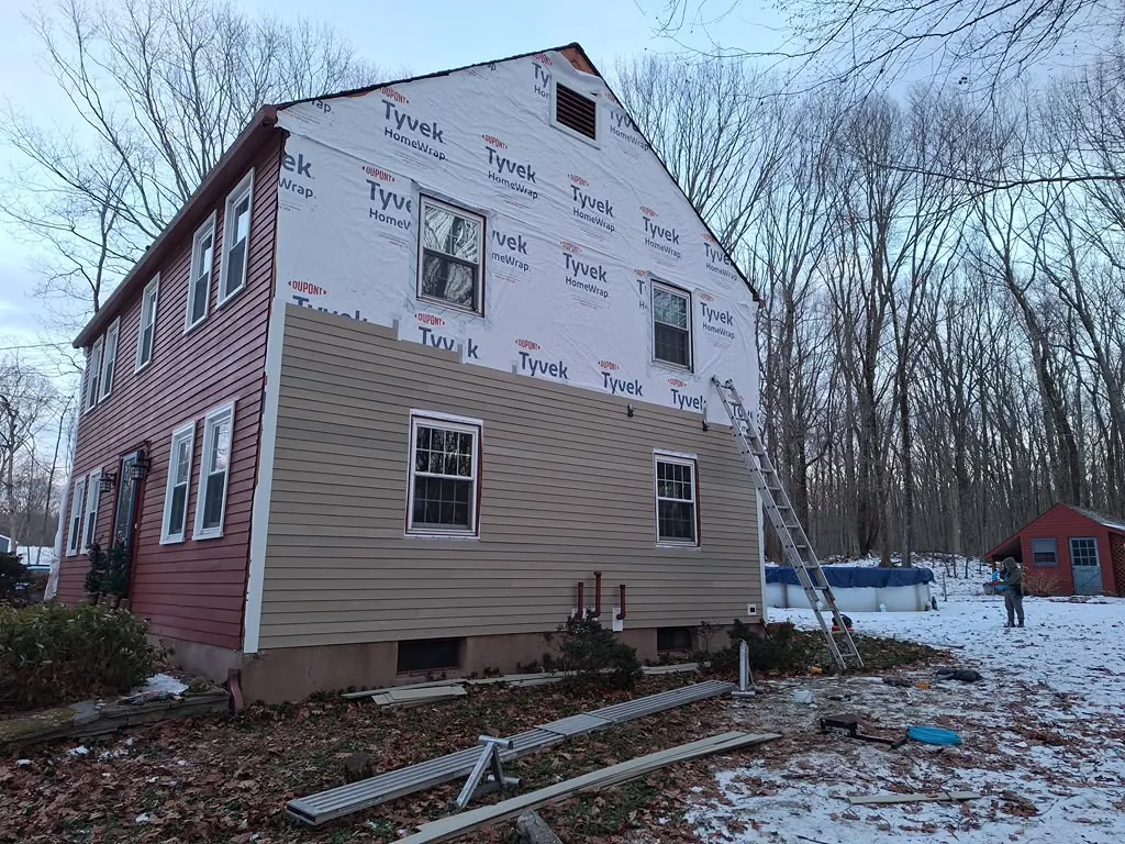 Home siding transformation from old red siding to new tan siding and house wrap